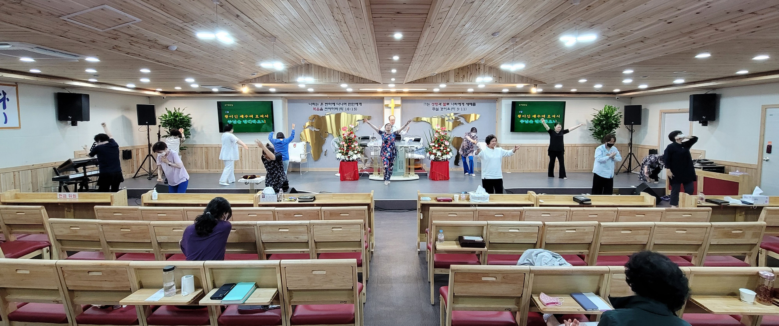 The Reverand Doctor (Pastor) Yong Doo Kim is leading church from behind the pulpit, while his wife & the women are exhaulting (glorifying & worshiping) The Lord through dancing.